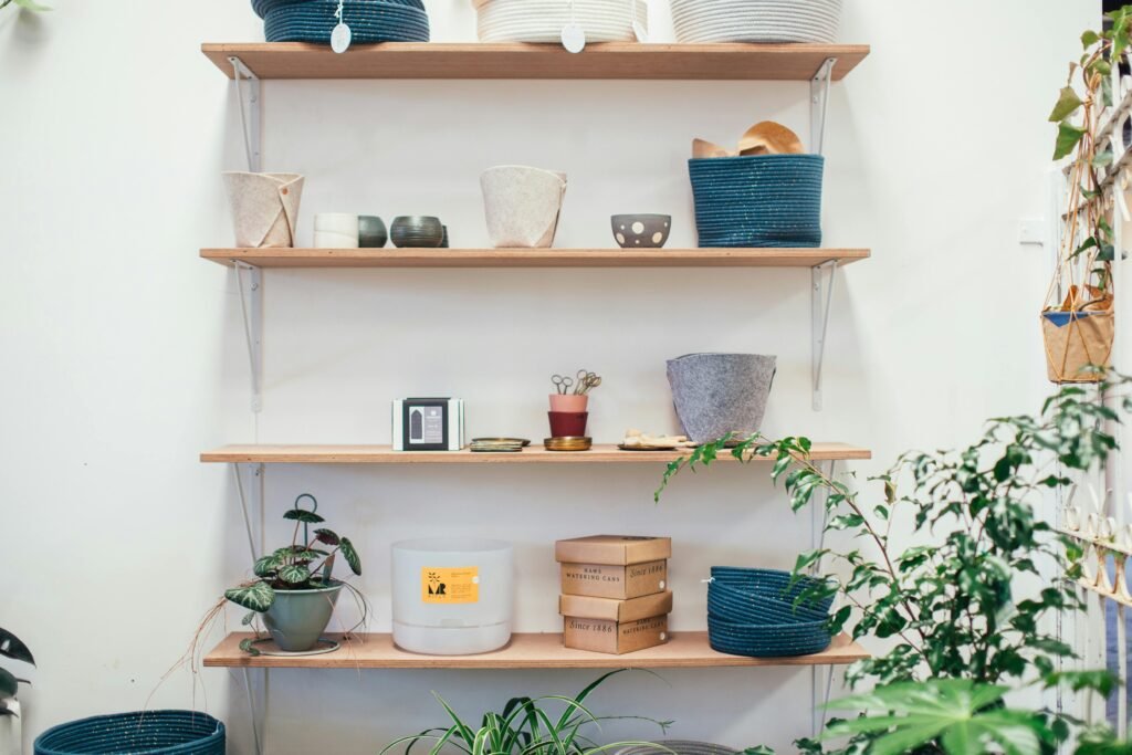 Many pots and carton boxes placed near bowls and green potted plants in apartment
